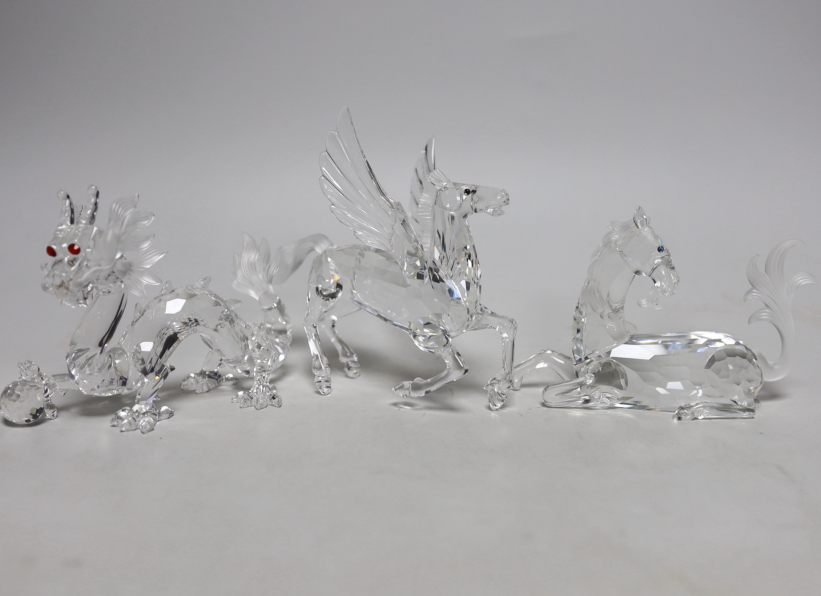 Three Swarovski Crystal figures comprising Pegasus, unicorn and dragon, each with boxes and booklets, the largest 15cm wide